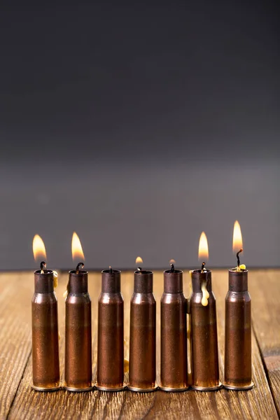 Brennende Kerzen und leere Gewehrpatronen. — Stockfoto