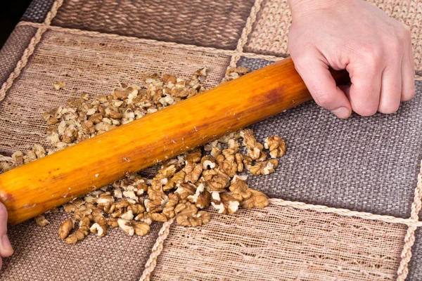 Hand mit Nudelholz und geriebenen Walnüssen. — Stockfoto