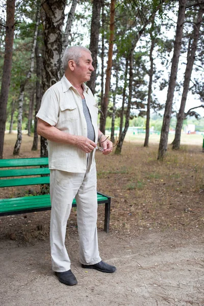 Bătrânul stă lângă bancă. . — Fotografie, imagine de stoc