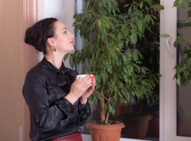 Bir fincan çay tutan iş kadın.