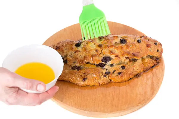 Hand schmiert Öl auf einen Kuchen. — Stockfoto