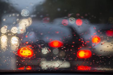 Yağmur damlaları ile araba penceresinden yol görünümü.