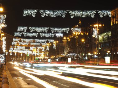 Noel çelenkleriyle süslenmiş kış festivali şehri yol boyunca farların bulanık olduğu arabalarla.