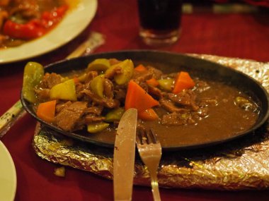 Çin mutfağından bir tabak et ve metal tabakta sebzeler.