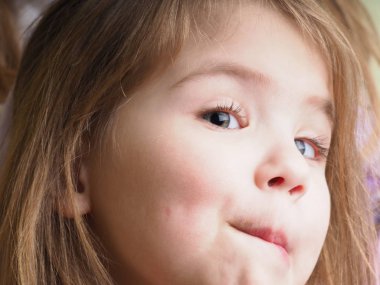 Gülümseyen küçük Ukraynalı sarışın kız tek gözüne düşen uzun saçlı.