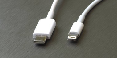 Gri metal arka planda Usb tip C ve şimşek beyaz kablo bağlantısı