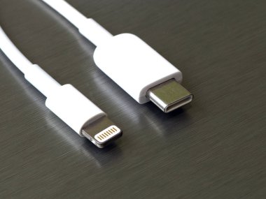 Gri metal arka planda Usb tip C ve şimşek beyaz kablo bağlantısı