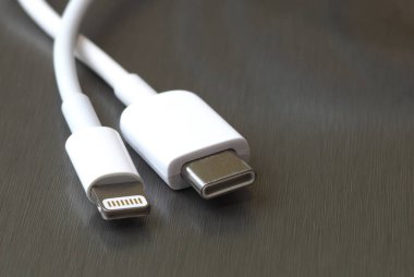 Gri metal arka planda Usb tip C ve şimşek beyaz kablo bağlantısı
