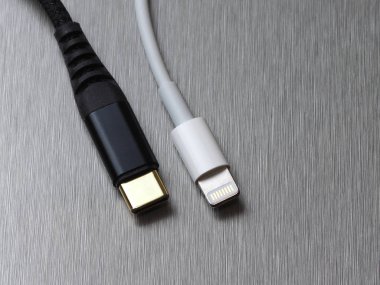 Gri metal arka planda Usb tip C ve yıldırım kablo bağlantısı