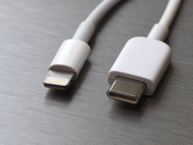 Gri metal arka planda Usb tip C ve şimşek beyaz kablo bağlantısı