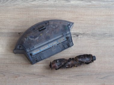 Cleaning the robot vacuum cleaner, filled garbage can cleaner, long hair wound on a robot  vacuum cleaner brush. 