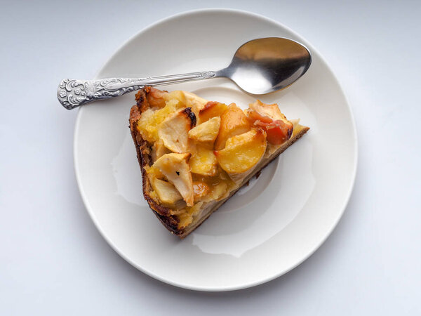 homemade apple pie on a white saucer with a spoon on a white background