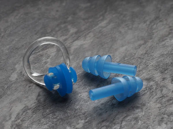 Nose clip and ear plugs for swimming pool on a gray background. Sport equipment. Set of earplugs for swimming and clamp on the nose