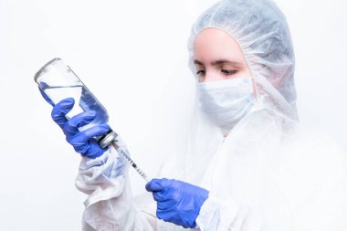 Beyaz maskeli ve viral koruyucu giysili mavi lastik eldivenli bir virüs uzmanı kameraya korkunç bir şekilde bakıyor ve koronavirüs salgınını nasıl durduracağını ve ne yapacağını düşünüyor. Gözlerindeki korku....