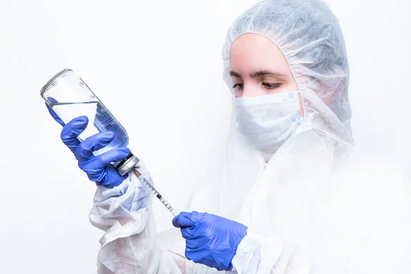 A virologist in a white mask and blue rubber gloves in a viral protective suit holds his head , looks fearfully at the camera and thinks about how to stop the coronavirus epidemic and what to do. The fear in his eyes.
