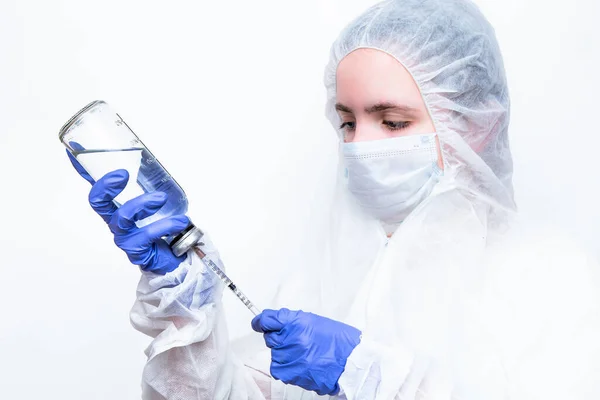 Beyaz maskeli ve viral koruyucu giysili mavi lastik eldivenli bir virüs uzmanı kameraya korkunç bir şekilde bakıyor ve koronavirüs salgınını nasıl durduracağını ve ne yapacağını düşünüyor. Gözlerindeki korku....
