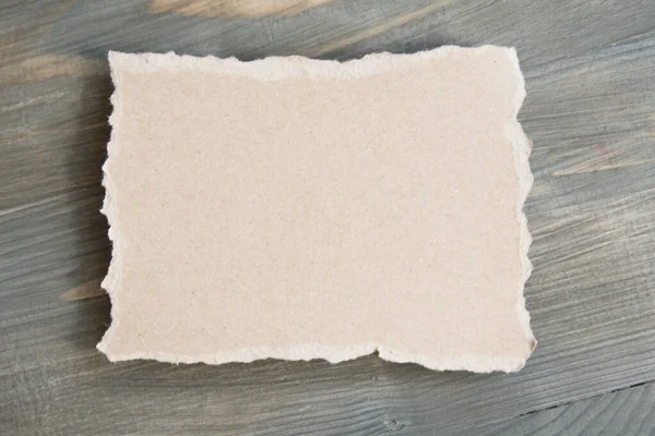 Piece of cardboard on wooden background — Stock Photo, Image