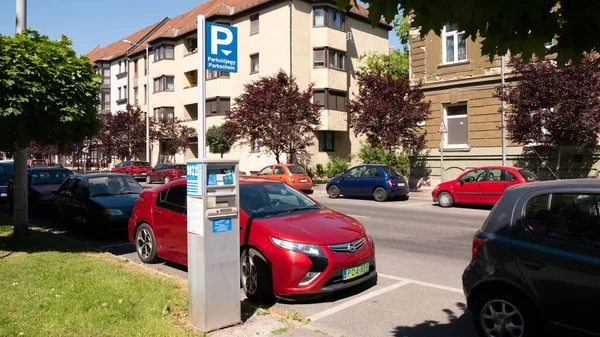 Gyor Macaristan 05: 21 2020: Yeşil bir plaka Opel Ampera elektrikli araba bir park cezası makinesinin yanında park edilmiştir. Macaristan 'da elektrikli arabaların park ücreti ödemesi gerekmez..