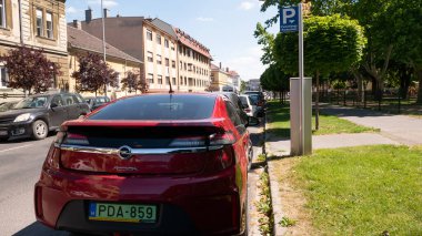 Gyor Macaristan 05: 21 2020: Yeşil bir plaka Opel Ampera elektrikli araba bir park cezası makinesinin yanında park edilmiştir. Macaristan 'da elektrikli arabaların park ücreti ödemesi gerekmez..