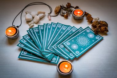 Kırmızı mumlu yeşil tarot kartları beyaz ahşap masa arkasında