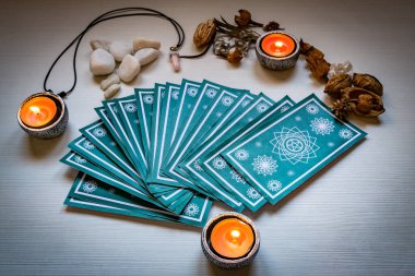 Green tarot cards with red candles on a white wooden table backg clipart