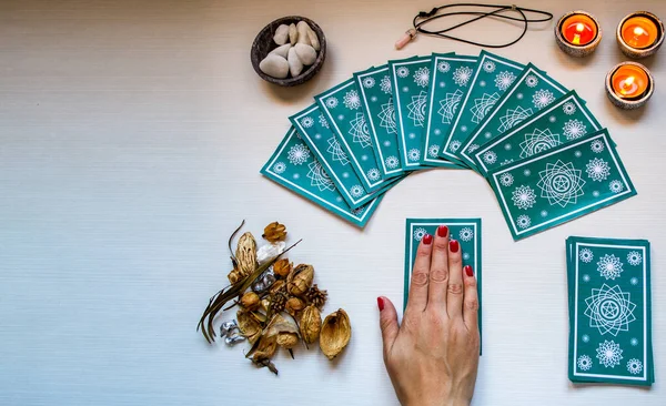 Beyaz tahta bir masada yeşil tarot kartlarıyla falcı.