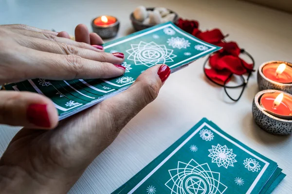 Beyaz tahta bir masada yeşil tarot kartlarıyla falcı.