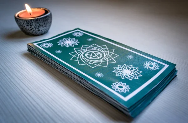 Green tarot cards with red candles on a white wooden table backg