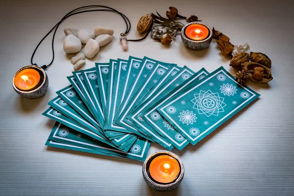 Kırmızı mumlu yeşil tarot kartları beyaz ahşap masa arkasında