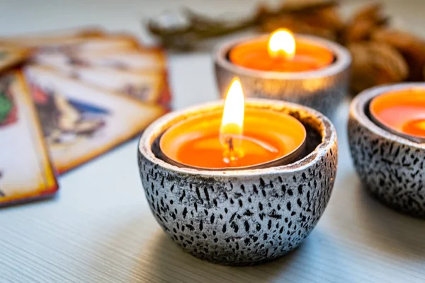 Beyaz ahşap bir arka planda kırmızı mumlu tarot kartları.