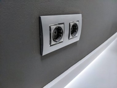 Koyu gri duvarda açık gri çerçeveli çift soket