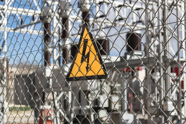 Elektrik santralini çevreleyen çitte sarı tehlike işareti