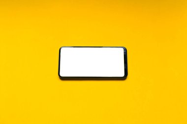 Yatay pozisyonda beyaz ekranlı akıllı telefon sarı arka planda izole edildi. Teknoloji konsepti