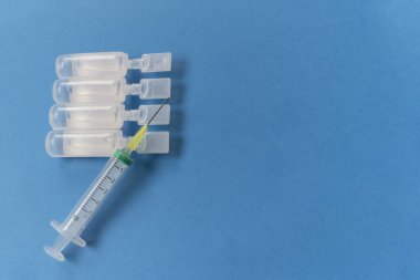 Mavi arka planda fizyolojik serum içeren şırıngalar. Tıbbi testler.