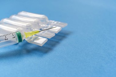 Mavi arka planda fizyolojik serum içeren şırıngalar. Tıbbi testler.
