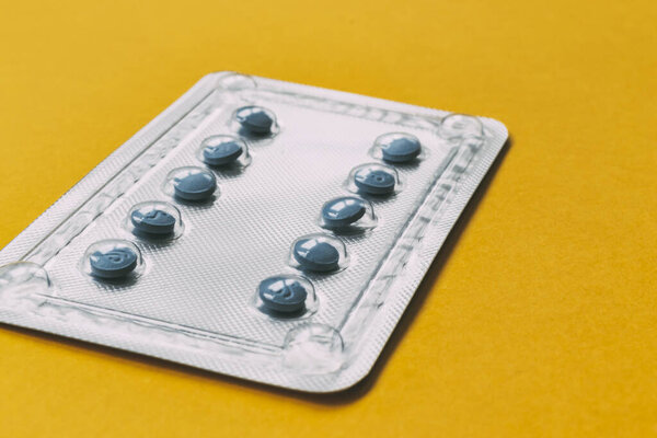 blue medicine blister pack on yellow background. medical concept