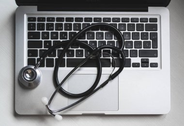 Stetoskop ve dizüstü bilgisayarı olan masaüstü masası, fotokopi alanı olan üst görünüm. Teletıp kavramı