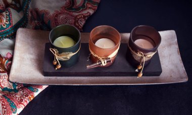 Original candle holder on a wooden base and and a colorful scarf.