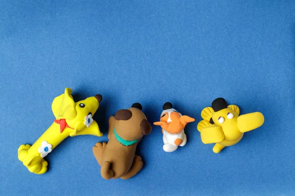 Four dogs from plasticine on a blue background — Stock Photo, Image