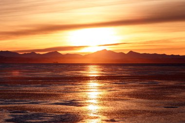 Dağlık sahil üzerinde bulutlu gündoğumu