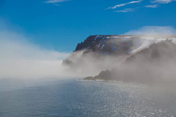Wysoki morze skały w śnieg i mgła. — Zdjęcie stockowe