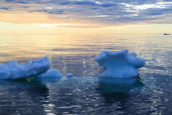 Лед в морской воде на фоне закатного неба — стоковое фото