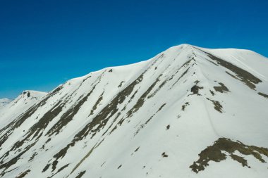 Güneşli bir havada karla kaplı dağların yamaçlarında.