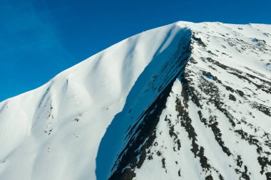 Güneşli bir havada karla kaplı dağların yamaçlarında.