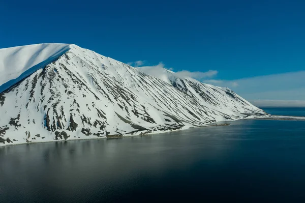 La costa montuosa del mare coperta di neve in un tempo soleggiato . — Foto Stock