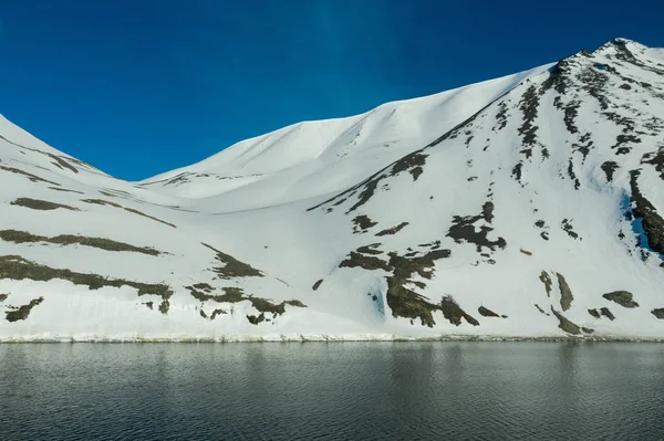 阳光明媚的时候，多山的海岸上覆盖着雪. — 图库照片