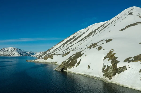 La costa del mar montañoso cubierto de nieve en un clima soleado . — Foto de Stock