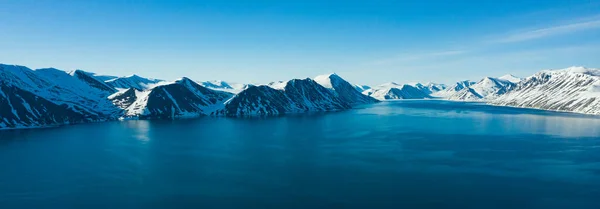 La costa del mar montañoso cubierto de nieve en un clima soleado . — Foto de Stock