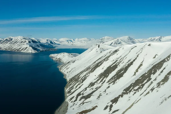 阳光明媚的时候，多山的海岸上覆盖着雪. — 图库照片