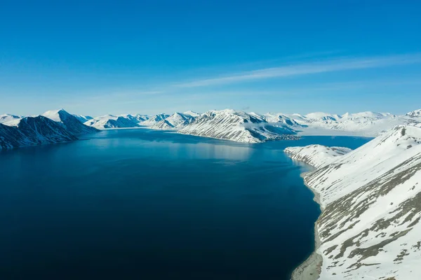 La costa montuosa del mare coperta di neve in un tempo soleggiato . — Foto Stock